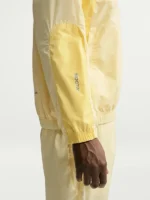 Right view of NOCTA Northstar Yellow Track Jacket with zipper closure, yellow fabric, and elastic cuffs