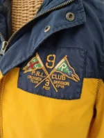 Close up detail of Polo Ralph Lauren PRL Club Cruiser Team Division 2745 Pier 3 embroidered badge on yellow navy colorblock sailing jacket chest