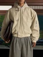 Full body model wearing beige Shinzo Shige canvas clasp bomber jacket with grey tailored trousers