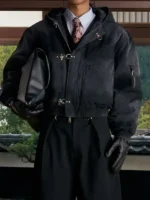 Full body editorial of black Shinzo Shige canvas clasp bomber jacket layered with long coat and formal tie