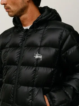 Close-up of black Stussy Hooded Puffer Jacket showing quilted nylon texture and hooded design