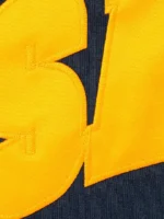 Close up detail of yellow gold tackle twill SALEM arch applique stitching on navy heavyweight fleece Supreme SALEM Zip Up Hooded Sweatshirt