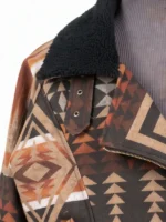 Close-up of a jacket neckline featuring an asymmetrical brass zipper, a black sherpa collar, and a decorative buttoned fabric strap.