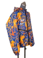 Three-quarter side view of the blue and orange FIFA World Cup 2026 Netherlands Anthem Jacket on a mannequin, showcasing the all-over graphic print of lions, gold chains, and tulips.