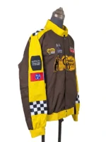 Right profile view of the NASCAR Cup Series Cracker Barrel 400 Racing Jacket on a stand, showing the yellow shoulder panel detailing, checkered sleeve inserts, and custom regional patches like the Tennessee state flag.