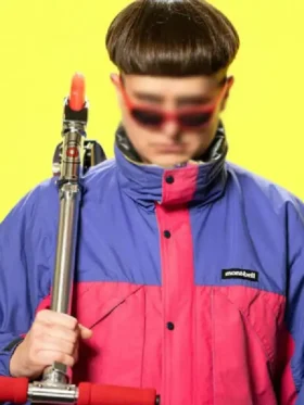 Oliver Tree wearing the Alien Boy pink and purple jacket while holding a scooter
