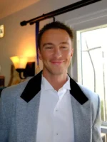 Front close-up of a man wearing the heather grey Drew Starkey blazer with wide black velvet peak lapels.