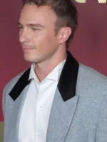 Close-up of a man wearing the heather grey Drew Starkey blazer with contrasting black velvet peak lapels.