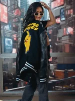 Woman carrying the black Pikachu varsity jacket over her shoulder, showing the yellow back patch in a city setting.